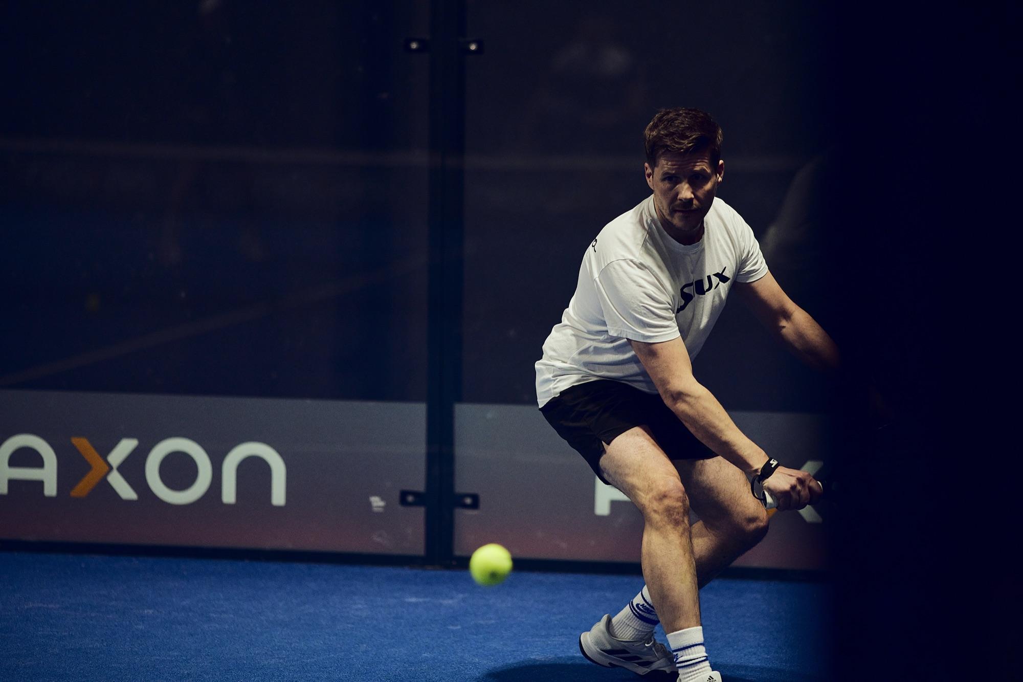Padel player mid-rally on an indoor court