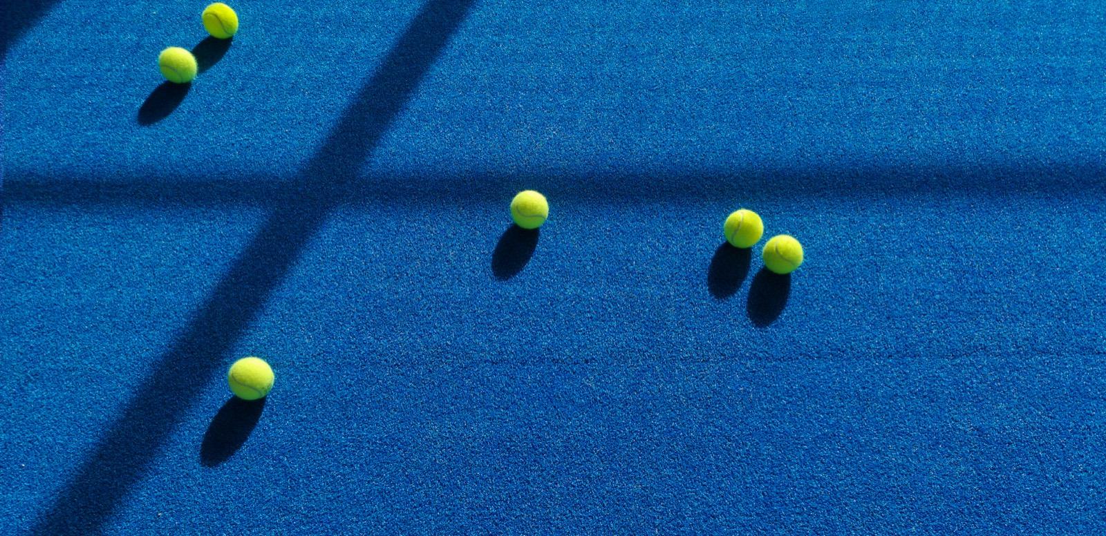 Padel balls on a wide blue court before play