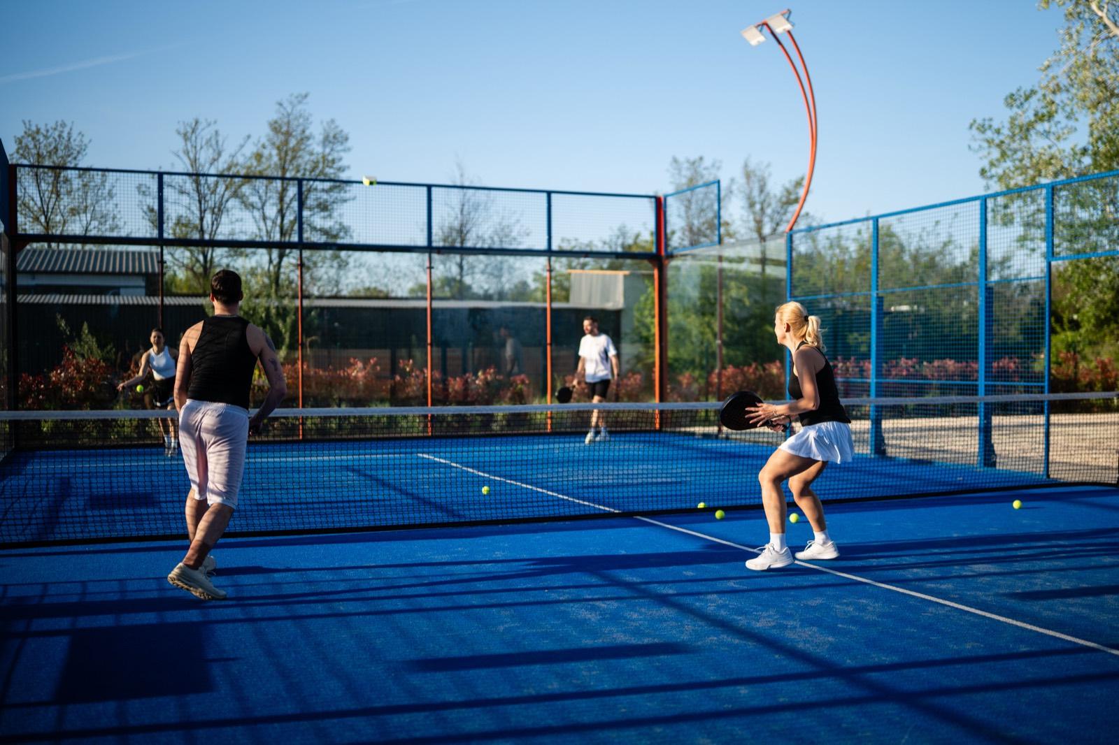 Four players in a doubles rally on an outdoor padel court