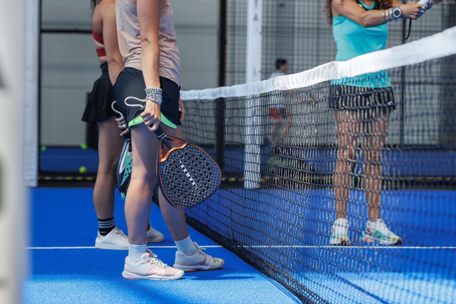 Two padel pairs playing at the net on an indoor court